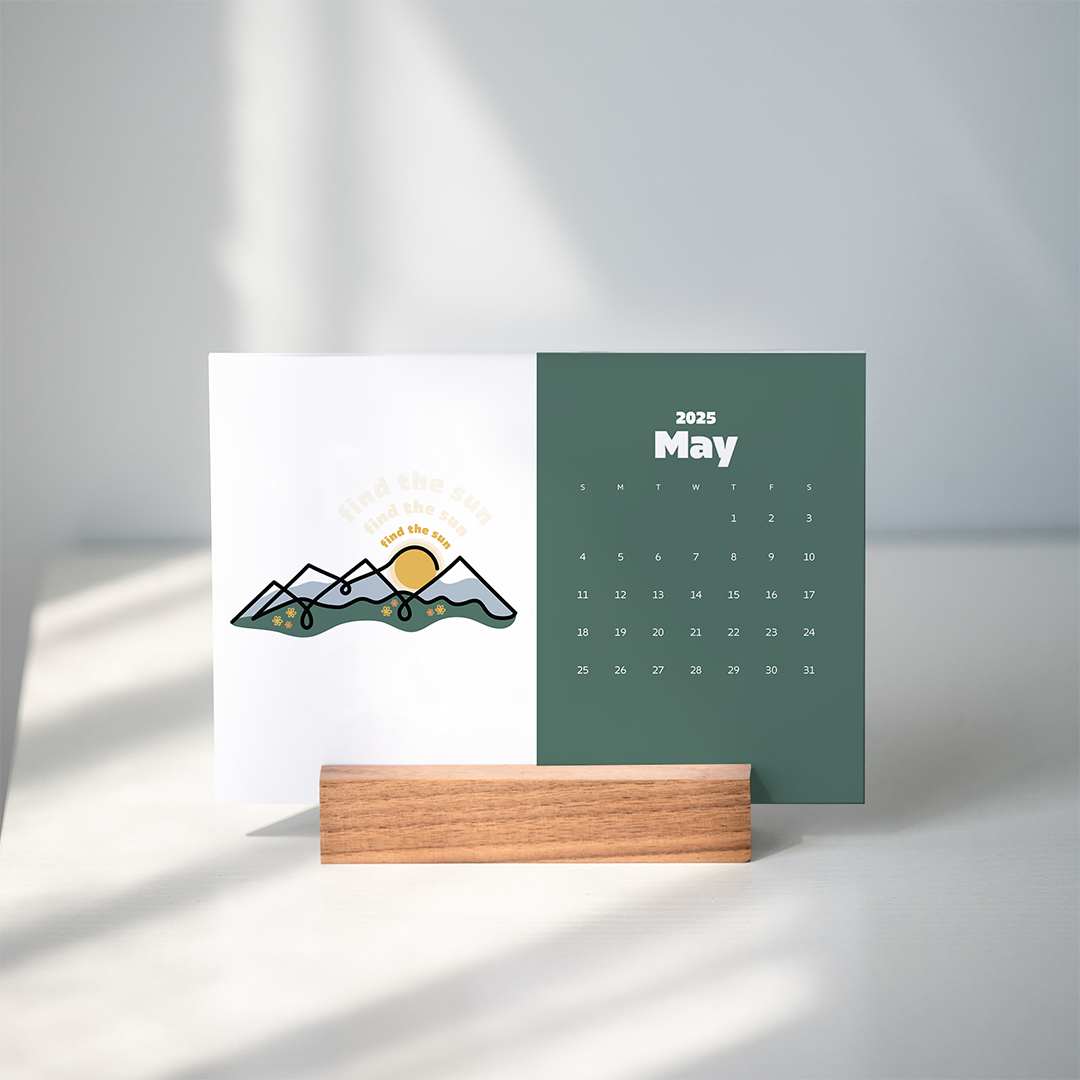 5x7 paper calendar with color block of green and CalmLines mountains illustration in wooden block.