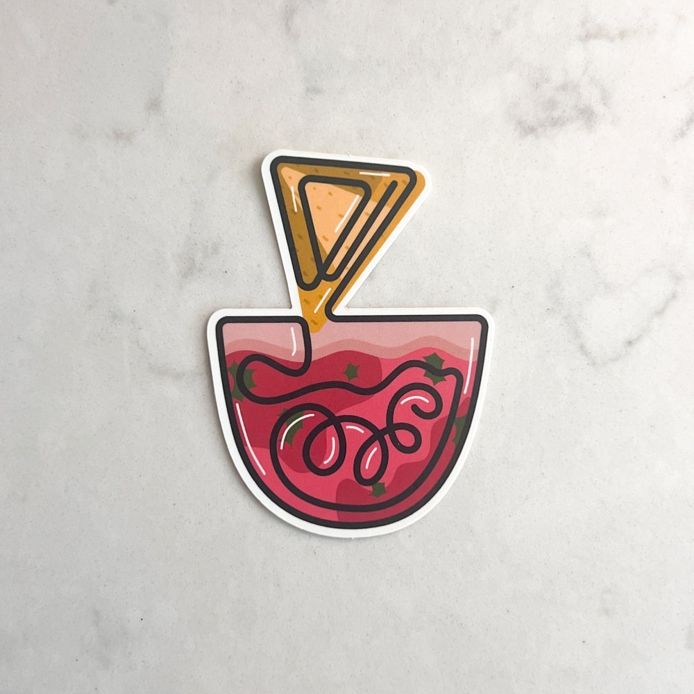 Sticker of a bowl of salsa with a chip taken out on a marble background