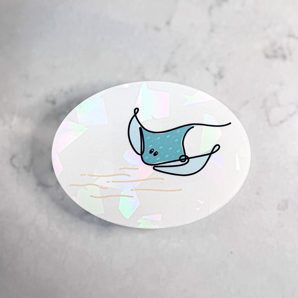 Oval-shaped sticker with a teal stingray design on a marble background