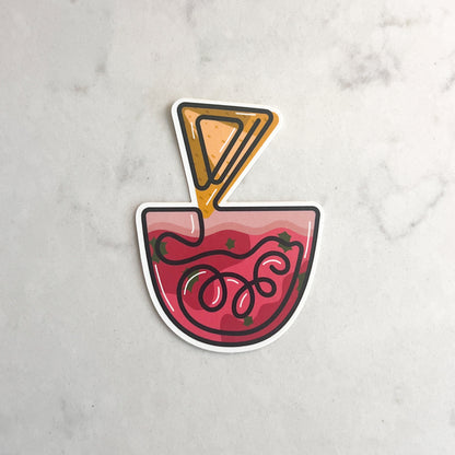 Sticker of a bowl of salsa with a chip taken out on a marble background